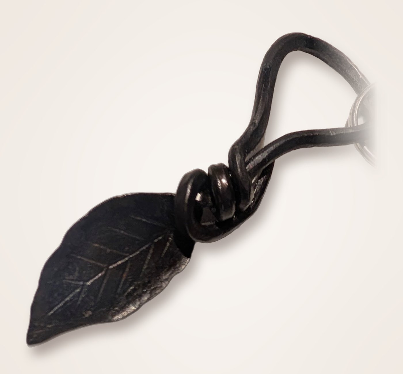 The Leaf Me Alone keychain: a blackened, hand-forged steel leaf with a coiled wrap and a teardrop loop