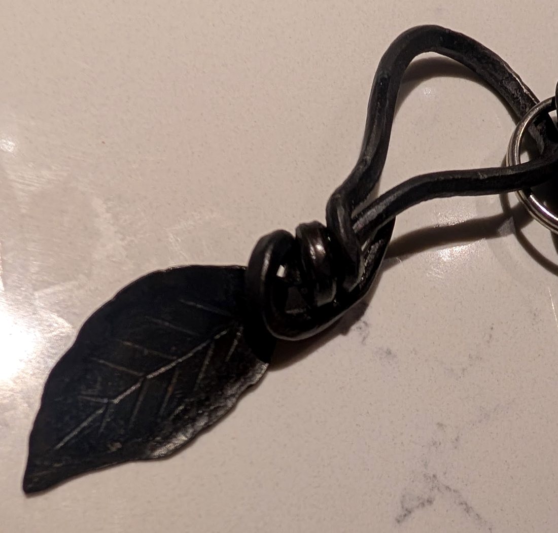 The steel leaf keychain clipped to a key ring on a marble counter